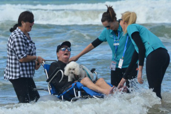 Community Palliative Care patient Tony Lambert returns to the surf in one of Gold Coast Health’s new beach wheelchairs.